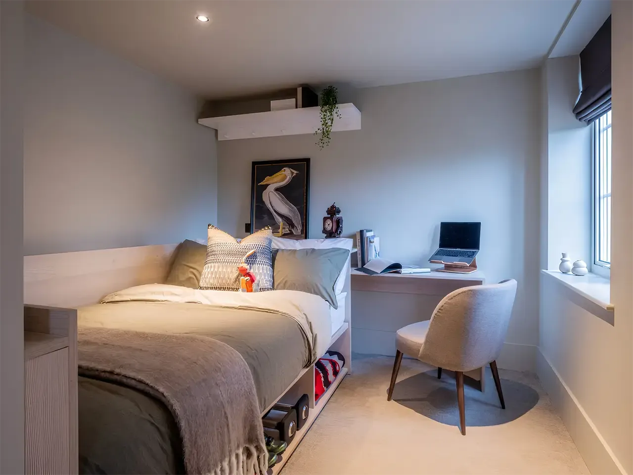 A modern bedroom with a cozy bed, built-in desk, and warm lighting.